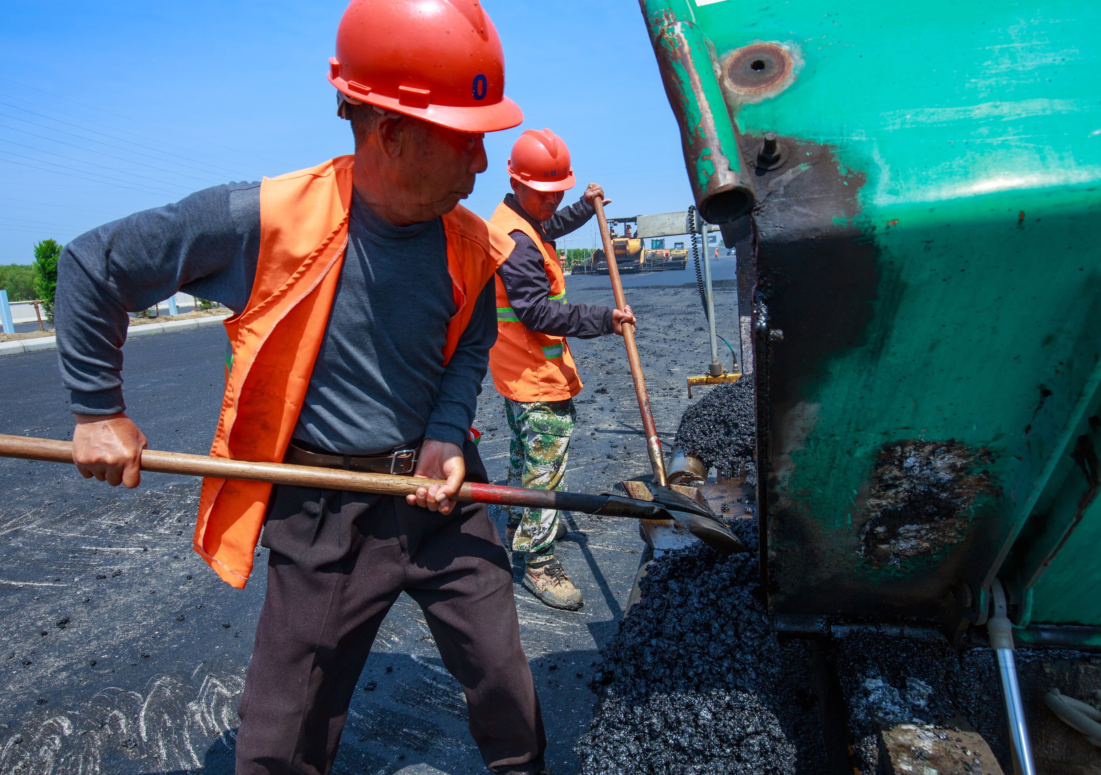 204国道盐阜快速通道沥青摊铺现场,辅助工在清理摊铺机料斗。.jpg 204国道盐阜快速通道沥青摊铺现场,辅助工在清理摊铺机料斗。.jpg